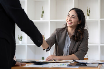 Smiling young businesswoman shaking hands with an office colleague