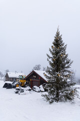 Beautiful little wooden mountain houses, huts with a yard full of equipment covered in snow on...
