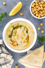 Classic hummus with parsley, olive oil, lemon and pita in a plate, top view. Arabic, Turkish...