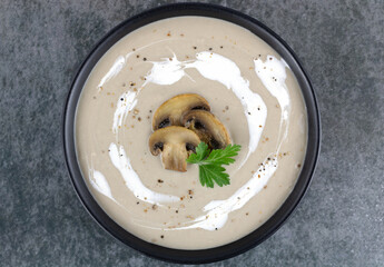 Mushroom cream soup on a gray wooden background. Porcini cream soup. Top view. Macro.