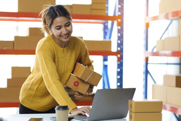 Woman who start up small business works in a warehouse. Startup entrepreneurs working with laptops...