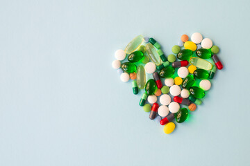 Heart made of colorful pills on blue background.