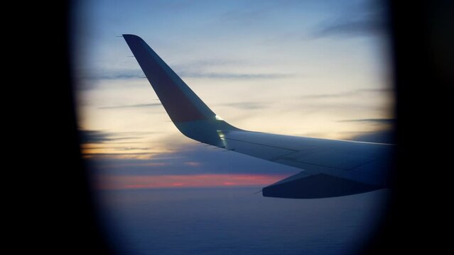 View from window on airplane wing and rays sun at dawn or sunset in flight at height. Beautiful view from above. Go on trip, vacation, adventure. Tourism and tourist. Colorful sky and white clouds.