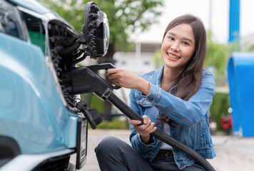Asia woman holding AC type 2 power cable plug connect to EV car at charging station. Car driven by electric motor engine for clean environment. Rechargeable vehicle concept. Ecology green technology