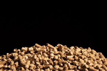 Many small compressed wooden sawdust of cylindrical shape are arranged in a heap on a black background. Cats toilet.