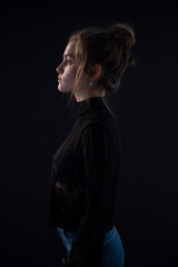 Profile portrait of a young woman, wear black suitcase, isolated black background.