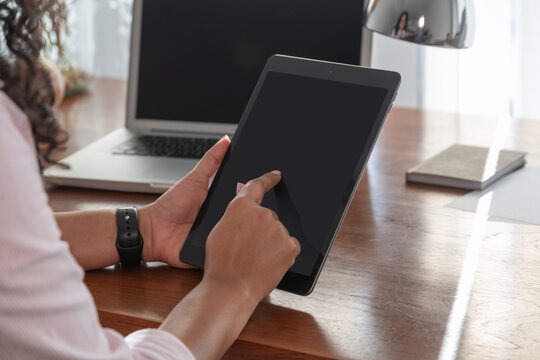 Focused anonymous ethnic woman working on digital tablet