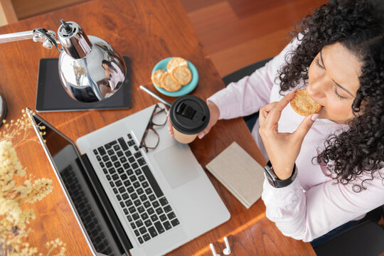 Woman with laptop having snack in home office