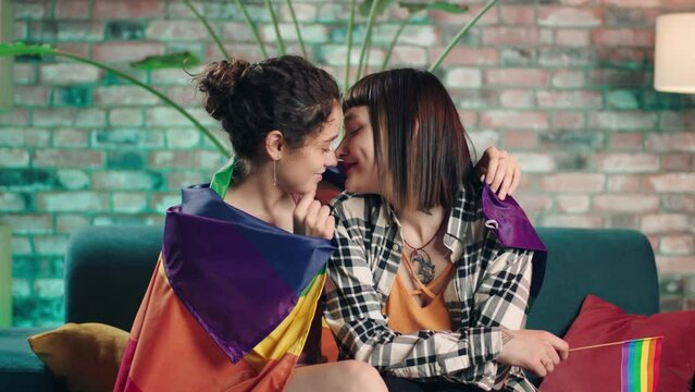 Charismatic and beautiful ladies lesbian couple very romantic spending time together they wanted to kiss each other they holding the LGBT rainbow flag on the back
