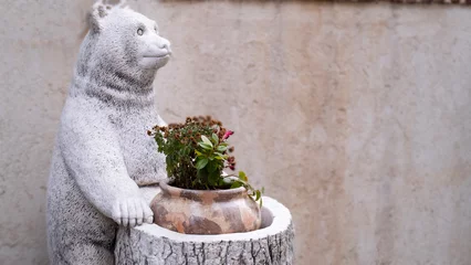 Fototapeten Bear statue made of stone presents its flowers © HAYRULLAH
