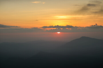 Beautiful sunset above mountains; the forest at orange sunset