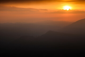 Beautiful sunset above mountains; the forest at orange sunset
