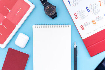 Vacation, trip or holiday planning concept - Public Holiday calendar with passport, notepad, pen, earphone, watch and tablet on blue background. Top view flat lay copy space.