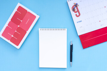 Vacation, trip or holiday planning concept - Public Holiday calendar with passport, notepad, pen, earphone and tablet on blue background. Top view flat lay copy space.