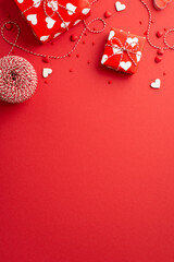 Valentine's Day concept. Top view vertical photo of present boxes spool of twine hearts and sprinkles on isolated red background with blank space