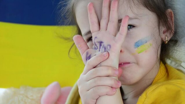 The girl is crying because of the war. War in Ukraine. A child with Ukrainian symbols. Children against war. Russian aggression against Ukraine. Ukrainian children are in fear. Peace concept. Stop war