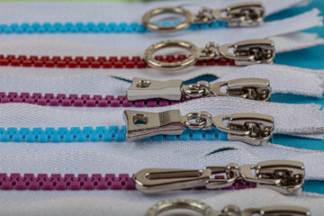 Fototapeta na wymiar Colorful Resin Zippers with Ring Pulls for DIY Tailor Sewing Craft Accessories Mixed. Bright zipper of different colors and variants in the textile industry.