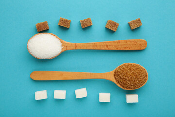 White and brown sugar in wood spoon on blue background.