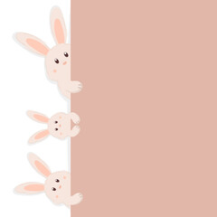 Fototapeta premium Cute Easter bunnies peeking out from behind the beige wall