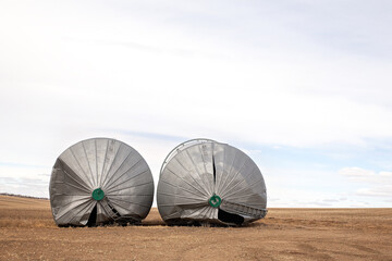 Front view of two steel grain bins toppled over from a windstorm in a rural autumn landscape
