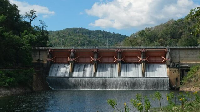 Hydroelectric dam, floodgate with flowing water through gate and open springway at Kew Lom Dam, Lampang, Thailand. Dam