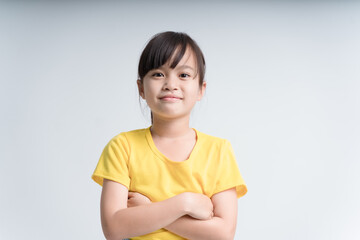 Portrait of cute swarthy asian little girl, arms crossed, beautiful happy child smiling and laughing looking at camera isolated in studio