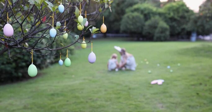 Two Children Wearing Bunny Ears when Pick Up painted Easter Egg Hunt In Garden or park. Cute caucasian baby and sister spending time together on backyard. Slow motion