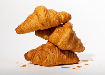 Three stacked fresh croissants, French bakery, sweet dough dessert composition with crumbs