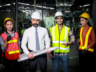 The multiethnic diverse group of engineers or business partners at the factory plant, working together on building's blueprint, architect industry or teamwork concept..