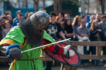 Medieval restorers fight with swords in armor at a knightly tournament, historical restoration of...