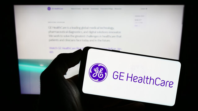 Stuttgart, Germany - 01-06-2023: Person holding mobile phone with logo of American company GE HealthCare Technologies Inc. on screen in front of web page. Focus on phone display.