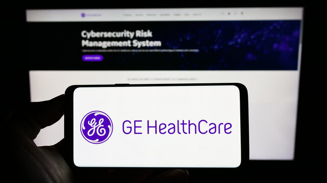 Stuttgart, Germany - 01-06-2023: Person holding cellphone with logo of US company GE HealthCare Technologies Inc. on screen in front of business webpage. Focus on phone display.