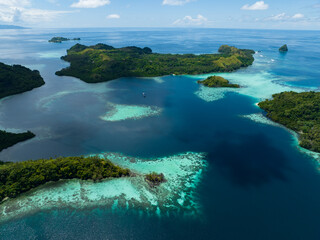 Extensive coral reefs fringe rainforest-covered islands in the Solomon Islands. This beautiful country is home to spectacular marine biodiversity and many historic WWII sites. - obrazy, fototapety, plakaty