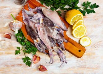 Fototapeta na wymiar Cooking ingredients, fresh raw calamari on wooden table