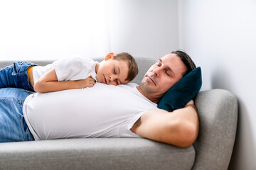 father with adorable little son on sofa at home lay on sofa