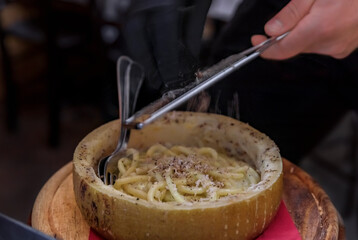 Fresh pasta with truffle sauce, cooked in a pecorino cheese wheel with shaved black truffles at an...