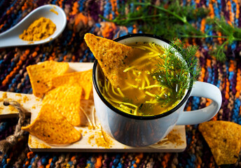 tasse mit heißer nudel-curry-suppe, currychips und fenchelkraut bei kalten Wintertagen