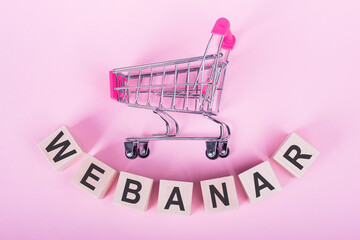 Mini shopping cart and wooden cubes with the text WEBINAR, pink background