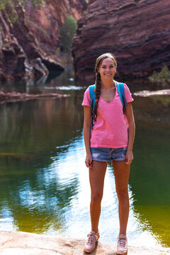 happy hiker girl standing inside a massive gorge in karijini national park, western australia; hiking in the australian outback
