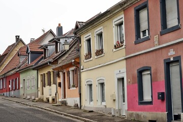 Fototapeta na wymiar Street in residential part of the town with traditional French architecture. The houses are painted in various colors. Above the entrance door of the nearest one there is written in French my paradise
