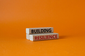 Building resilience symbol. Wooden blocks with words Building resilience. Beautiful orange background. Business and Building resilience concept. Copy space.