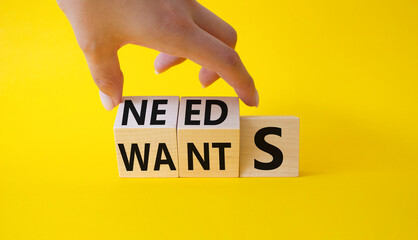 Needs and Wants symbol. Businessman Hand turns cubes and changes word Wants to Needs. Beautiful yellow background. Business and Needs and Wants concept. Copy space