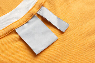 Blank white laundry care clothes label on yellow fabric texture background
