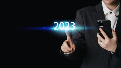 A businessman's fingers touching the number 2023 in preparation for a new target change. about investment, finance, goal planning