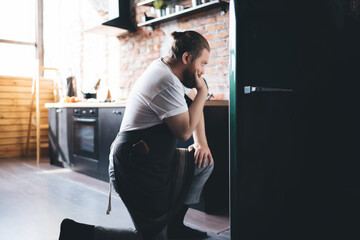 Man looking into fridge and touching chin