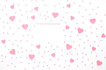 Blank white greeting card mockup among pink paper hearts on white background. Holiday, Valentine's Day, wedding concept.