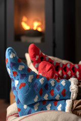 winter socks with hearts patterns in the background pellet stove lit, two pairs of feet boy and girl, couple inside warm and comfortable.