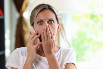 Stressed and shocked woman talking on smartphone and looking at camera.