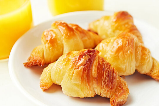 Close-up of a plate of traditional Argentinian medialunas and two glasses of orange juice