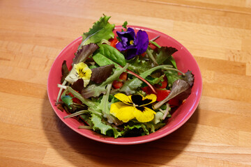 Beautiful mix salad with flowers on a wooden table. Diet concept. Healthy vegan food